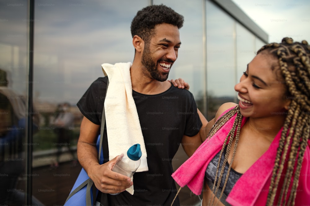 Um jovem casal conversando após o exercício ao ar livre no terraço, esporte e conceito de estilo de vida saudável.