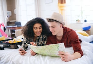 A cheerful young couple preparing and packing for summer holiday at home, planning.