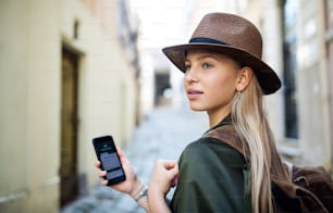 Portrait of young woman traveler in city on holiday using smartphone, sightseeing.