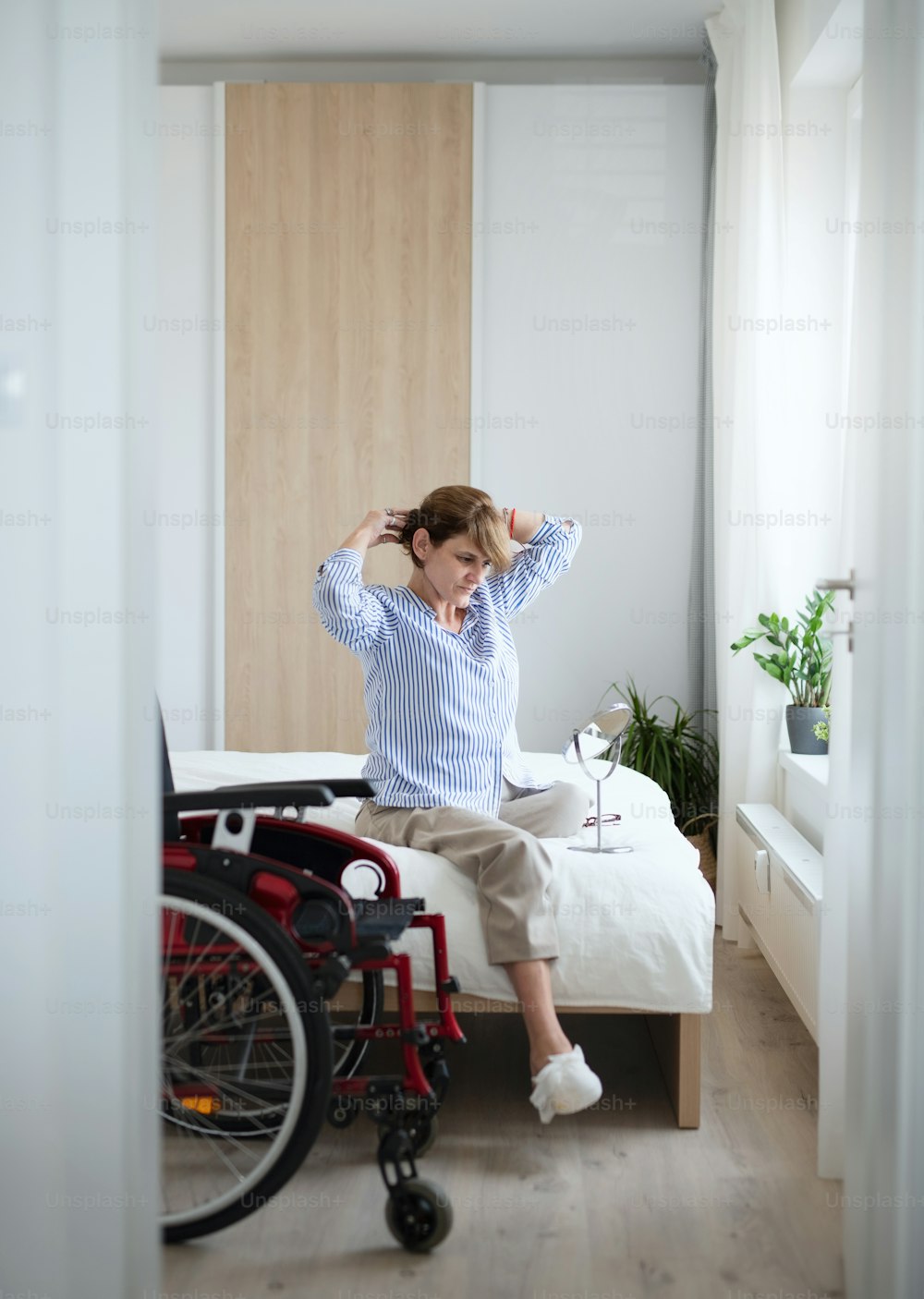 Ritratto di donna matura disabile seduta sul letto all'interno di casa, routine mattutina con concetto di amputato della gamba.