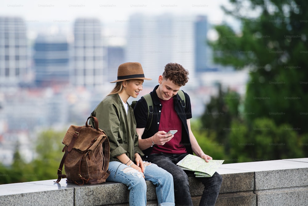 Portrait of young couple travelers with map in city on holiday, using smartphone.