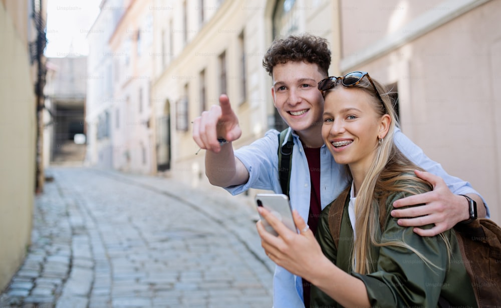 A young couple travelers using smartphone in city on holiday, sightseeing.