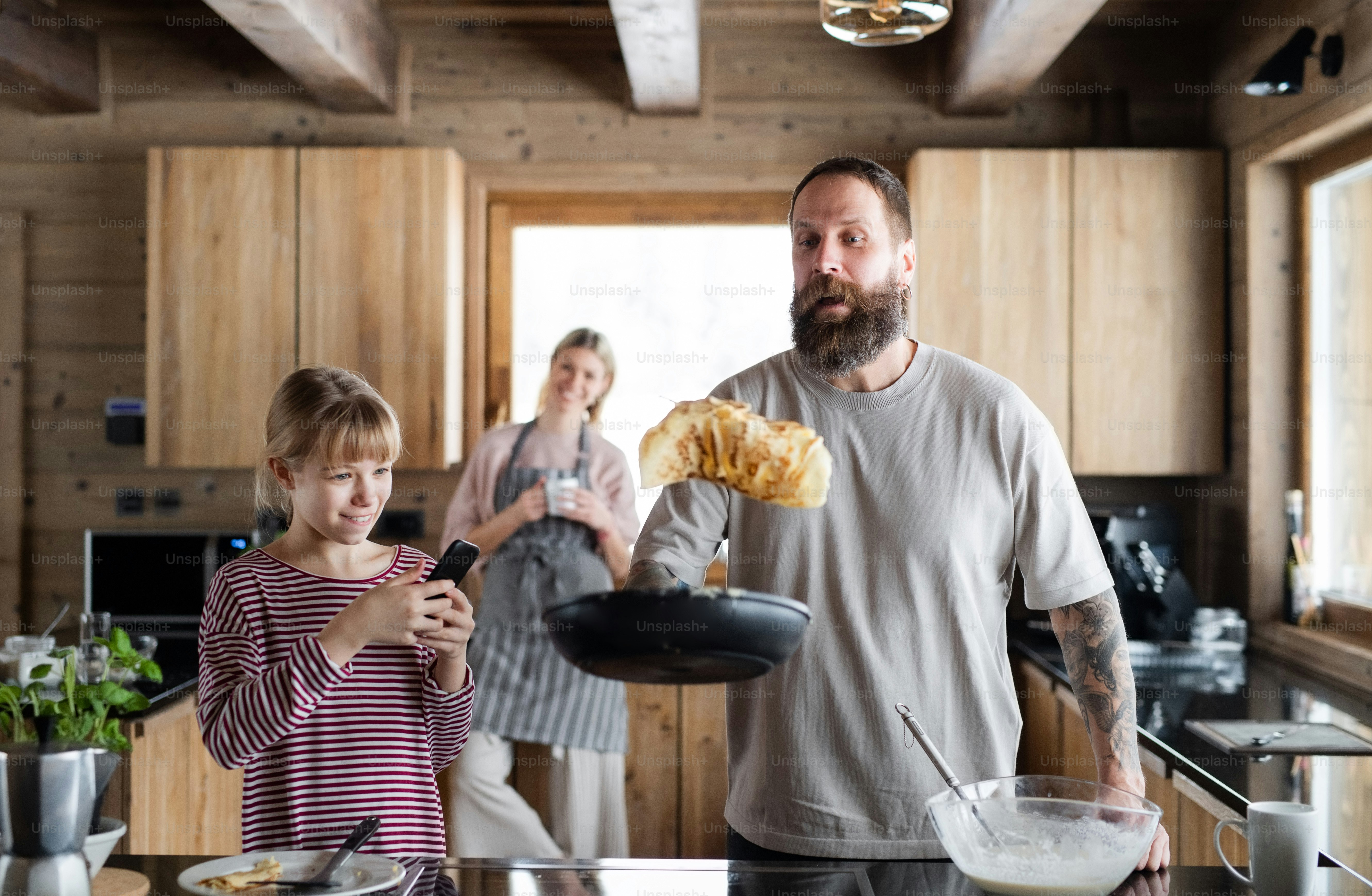 Família feliz com a filha pequena cozinhando dentro de casa, férias de inverno em apartamento privado