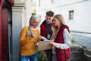 Young door to door volunteers talking to senior woman and taking a survey at her front door.