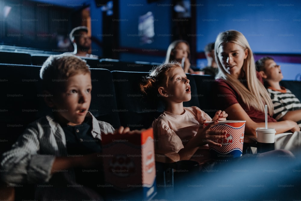 映画館で映画を見ながら幸せな小さな子供を持つ母親。