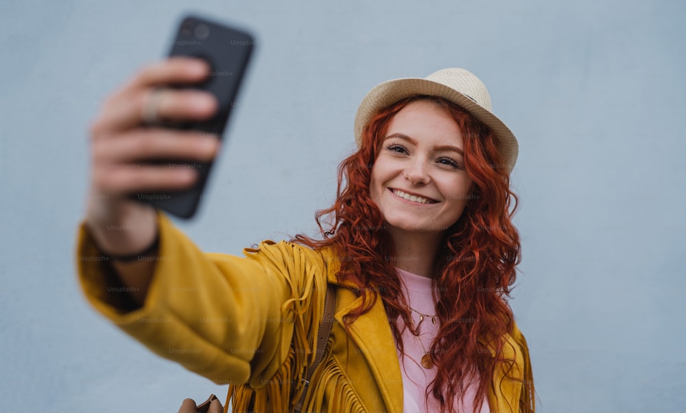 A young woman tourist outdoors against white background on trip in town, taking selfie.