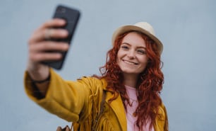Una giovane donna turista all'aperto su sfondo bianco in viaggio in città, scattando selfie.
