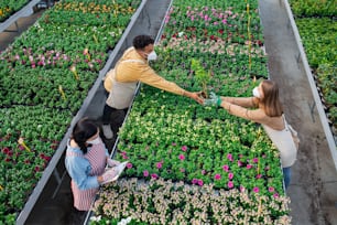 정원 센터, 코로나바이러스 개념의 온실에서 일하는 사람들의 상위 뷰.