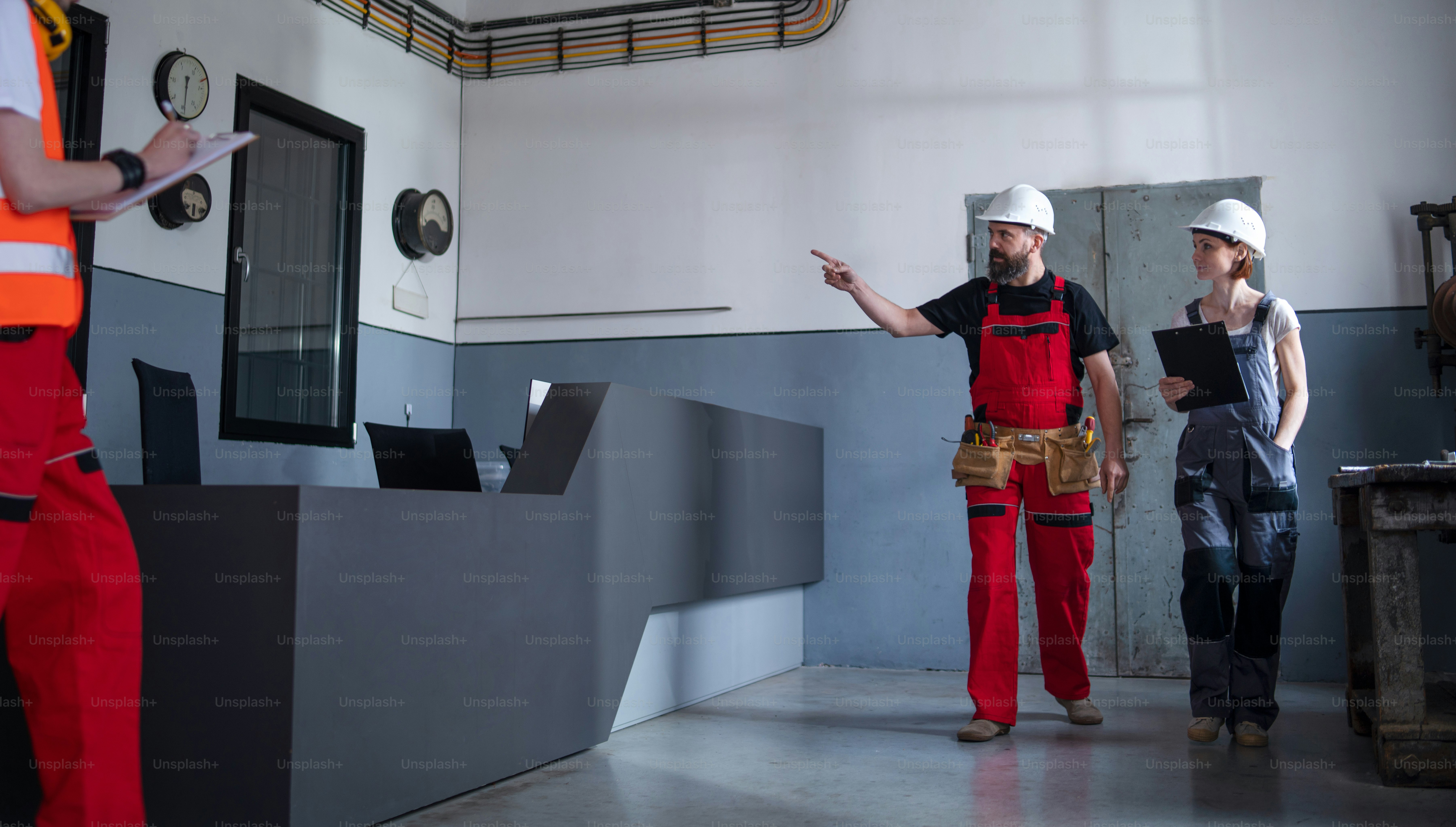 공장 실내에서 헬멧을 쓴 노동자 그룹이 문제를 논의하고 있습니다.