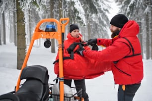La mujer paramédica del servicio de rescate de montaña realiza una operación al aire libre en invierno en el bosque.