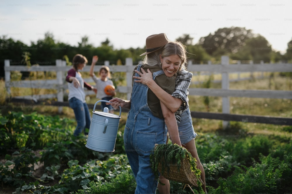 Una felice contadina adulta che abbraccia il suo coetaneo anziano che tiene un cesto con verdure coltivate in casa all'aperto presso la fattoria della comunità.