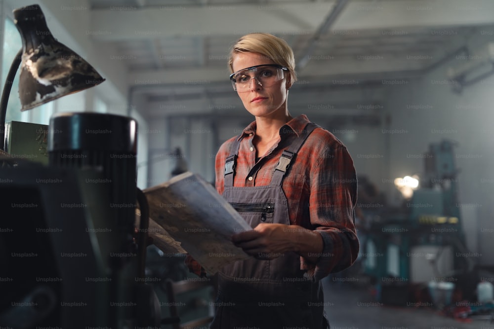 Um retrato de uma jovem mulher industrial que trabalha dentro de casa em uma oficina de metal.