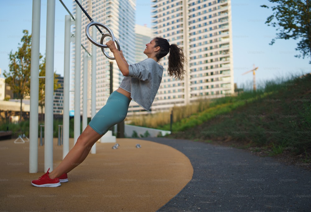 Mulher adulta média fazendo exercício em um tapete ao ar livre na cidade, conceito de estilo de vida saudável.