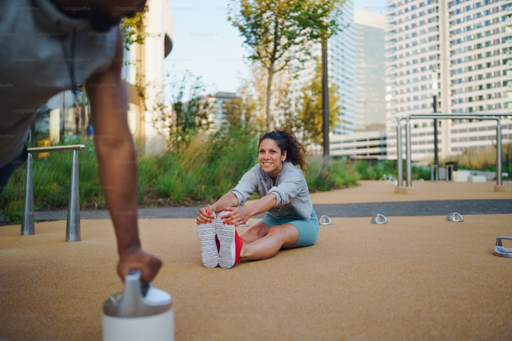 Happy man and woman couple friends doing workout exercise outdoors in city, talking.