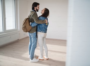Una giovane coppia che si abbraccia e si trasferisce in un nuovo appartamento, una nuova casa e un concetto di trasferimento.