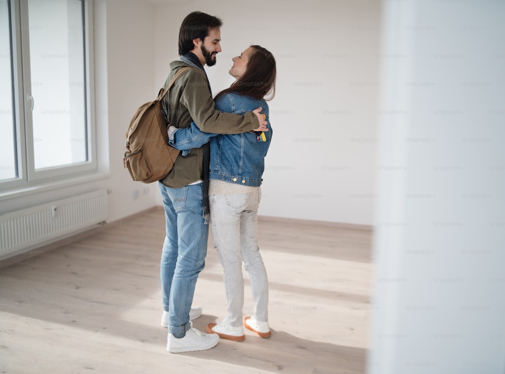 A young couple hugging and moving in new flat, new home and relocation concept.