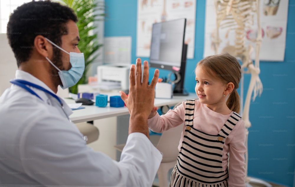 A little girl at doctor's office on, high fiving with doctor.