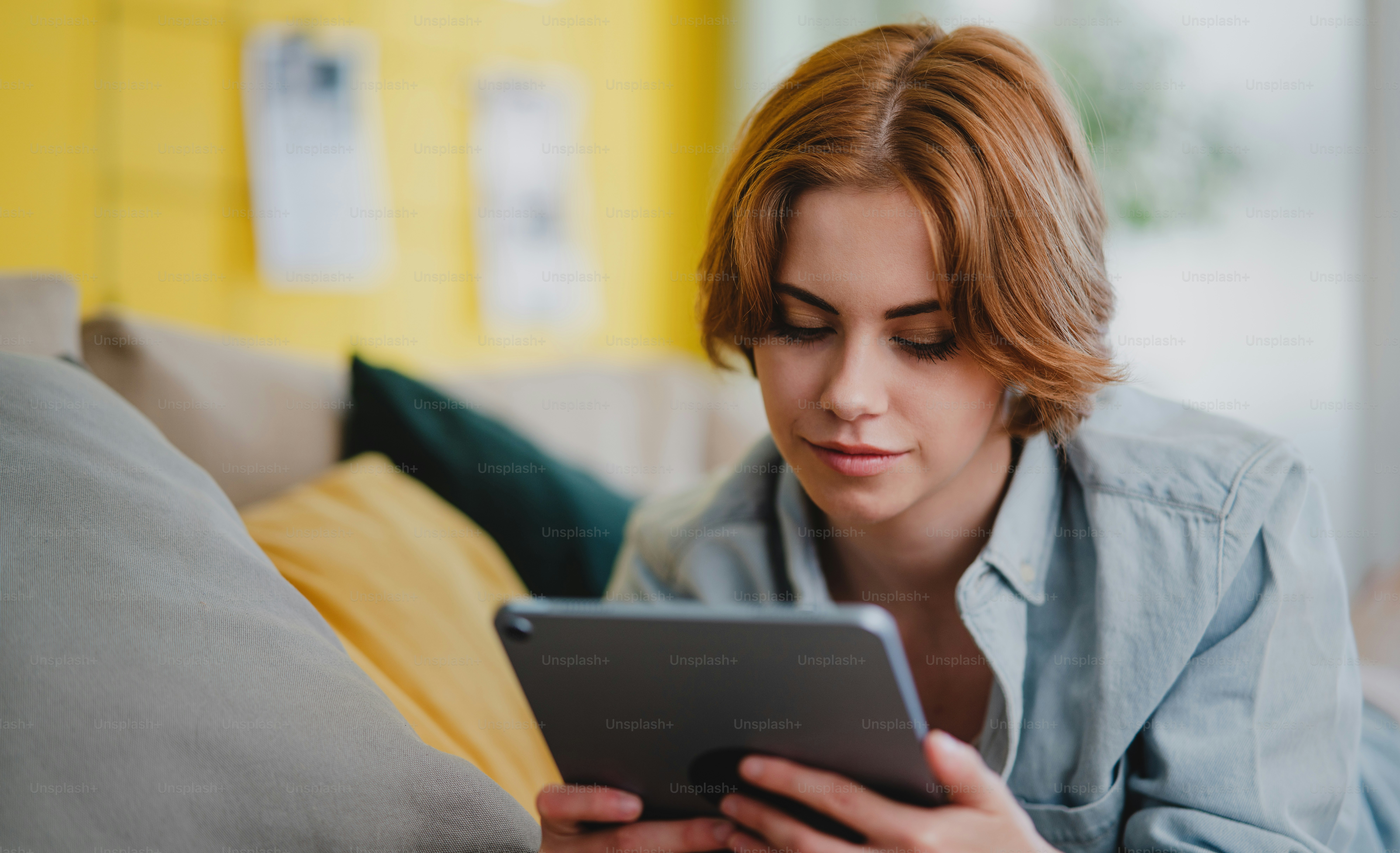 Portrait of a young woman using smartphone, lying on sofa at home, social networks concept.