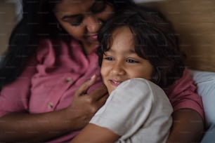 Eine Nahaufnahme einer indischen Mutter, die ihren kleinen Sohn zu Hause umarmt.