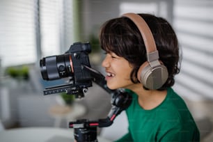 Un heureux garçon multiracial caméraman amateur avec des écouteurs à la maison.