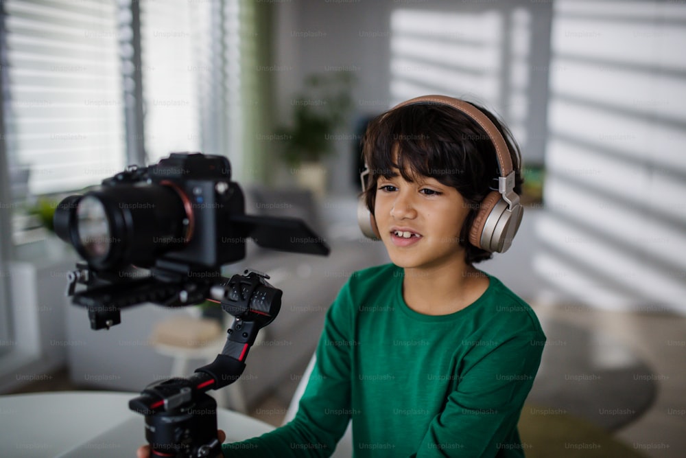 A happy multiracial boy cameraman amateur with headphones at home.