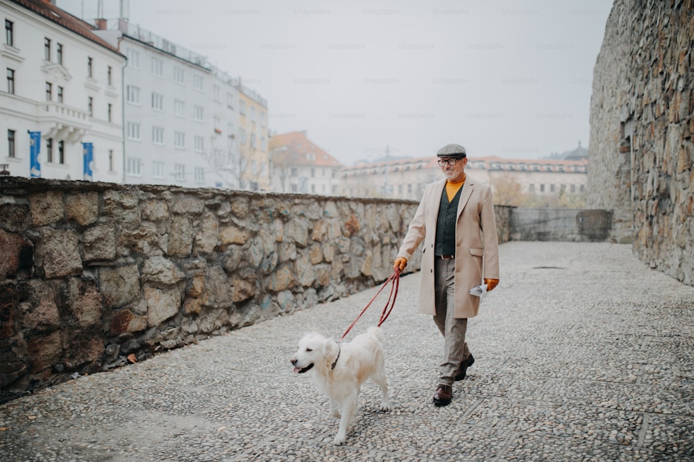Um homem idoso elegante e feliz passeando com seu cachorro ao ar livre na cidade.