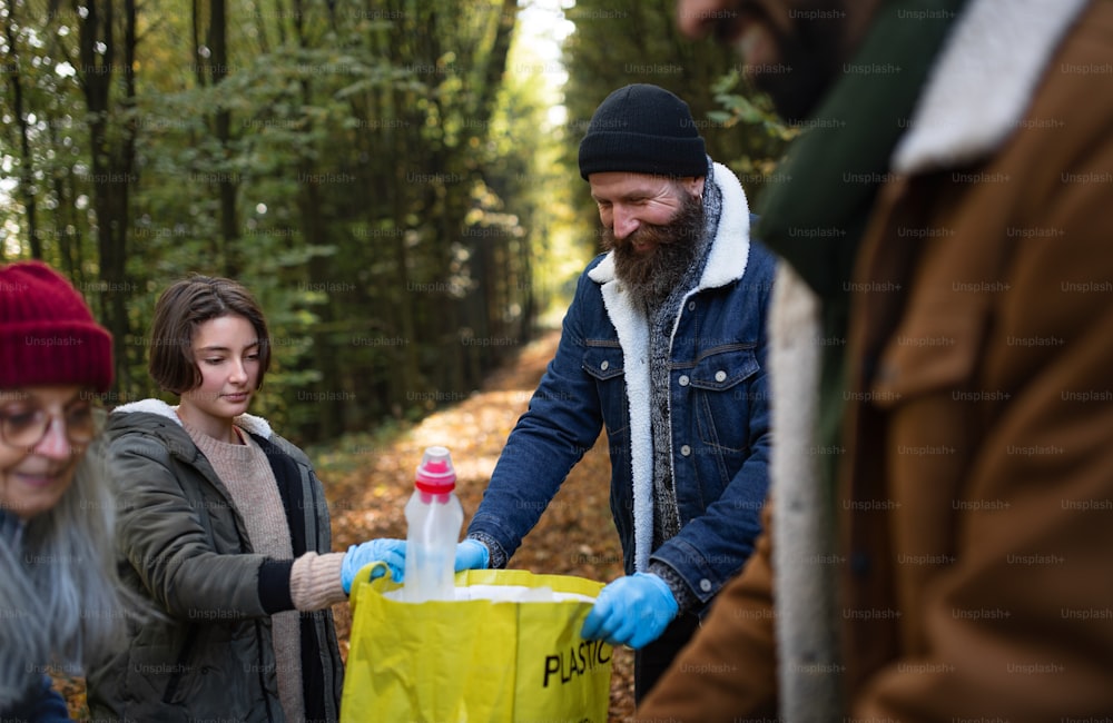 Un gruppo eterogeneo di volontari ripulisce la foresta dai rifiuti, concetto di servizio alla comunità