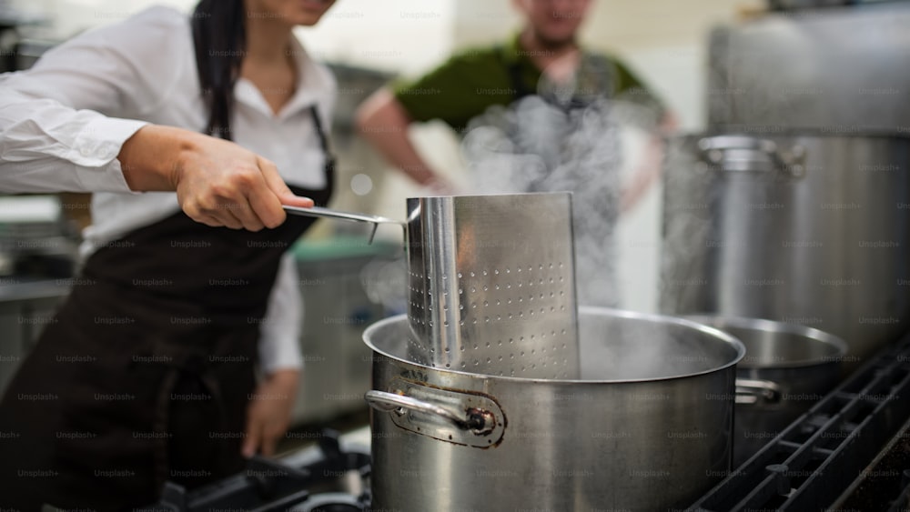 Uno chef e un cuoco irriconoscibili che cucinano insieme all'interno della cucina del ristorante.