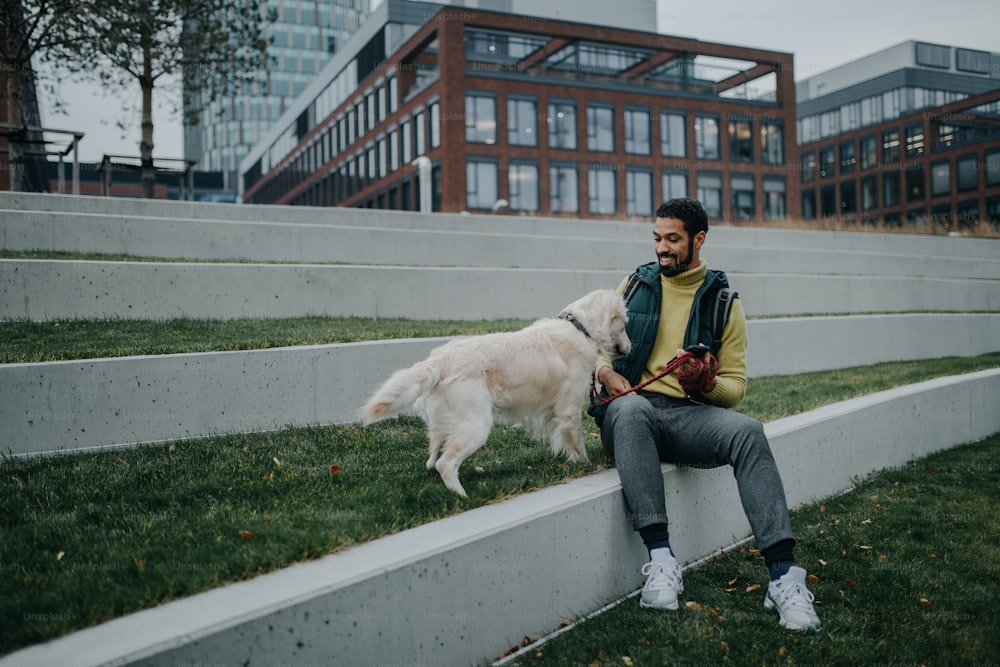 Un joven feliz tumbado en la hierba con su perro al aire libre en la ciudad.