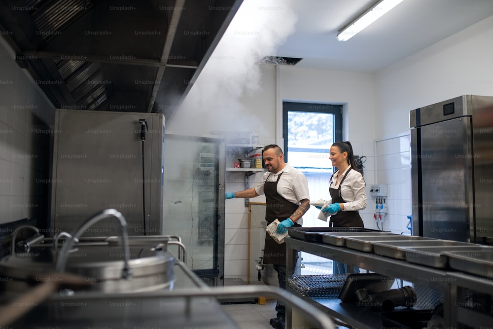 A chef and cook working on their dishes indoors in restaurant kitchen.