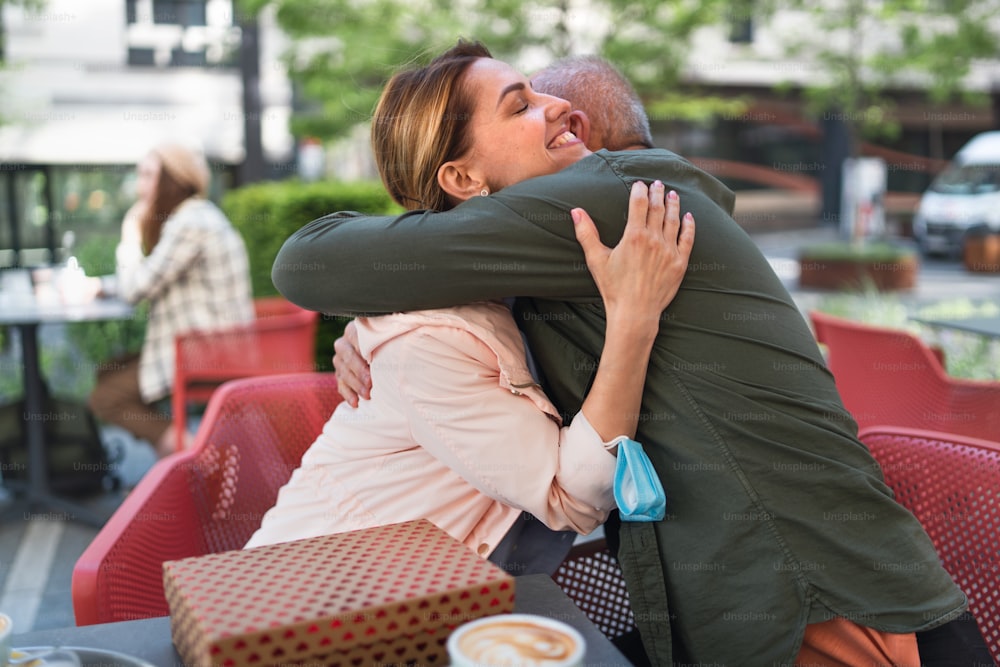 Happy woman hugging senior father outdoors in city, life after covid-19 vaccination and back to normal concept.