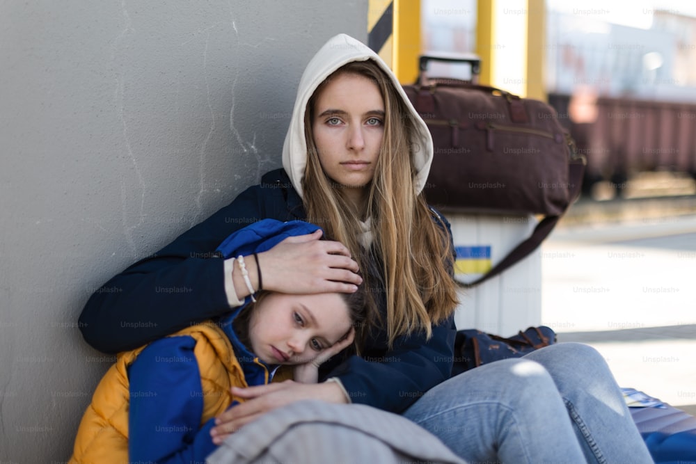 Imigrantes ucranianos deprimidos sentados e esperando em uma estação ferroviária.
