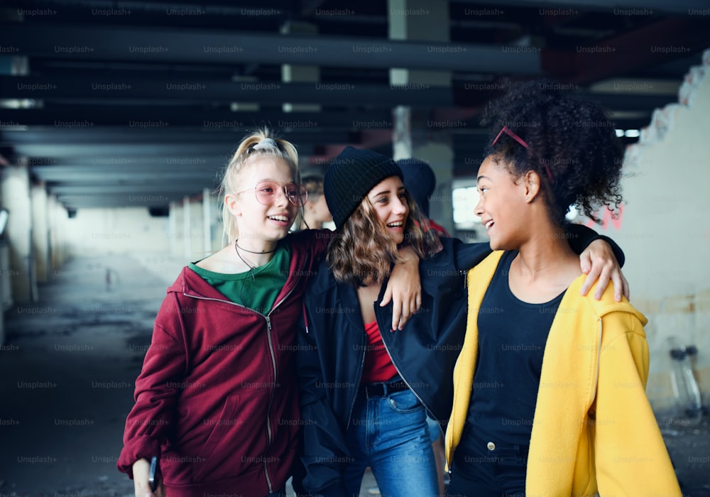 Front view of group of teenagers girl gang standing indoors in abandoned building, hanging out.