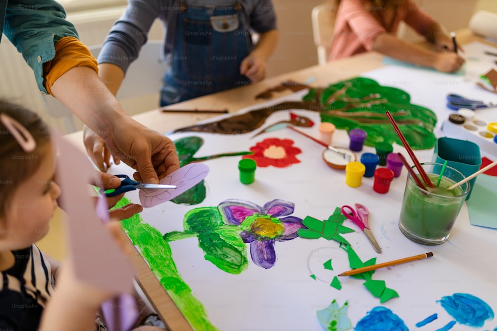 学校での創造的なアートとクラフトのクラス中に教師と一緒にプロジェクトに取り組んでいる小さな子供たちのクロエアップ