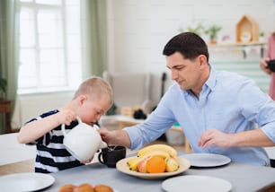 다운 증후군 아들을 가진 행복한 가족이 식탁에서 아침을 먹고 있습니다.