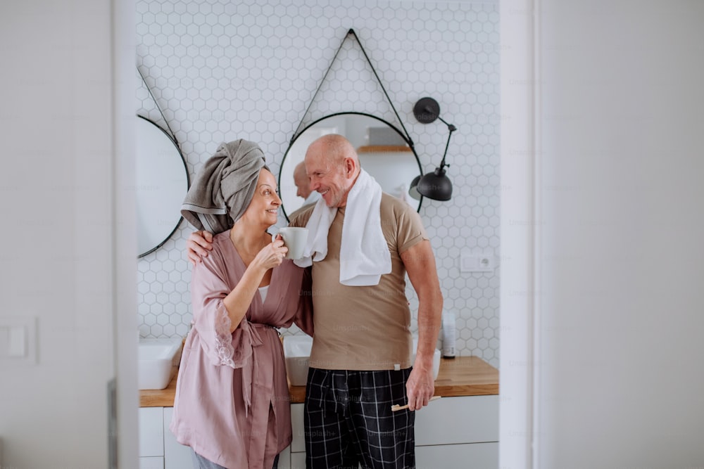 A senior couple in bathroom, brushing teeth and talking, morning routine concept.