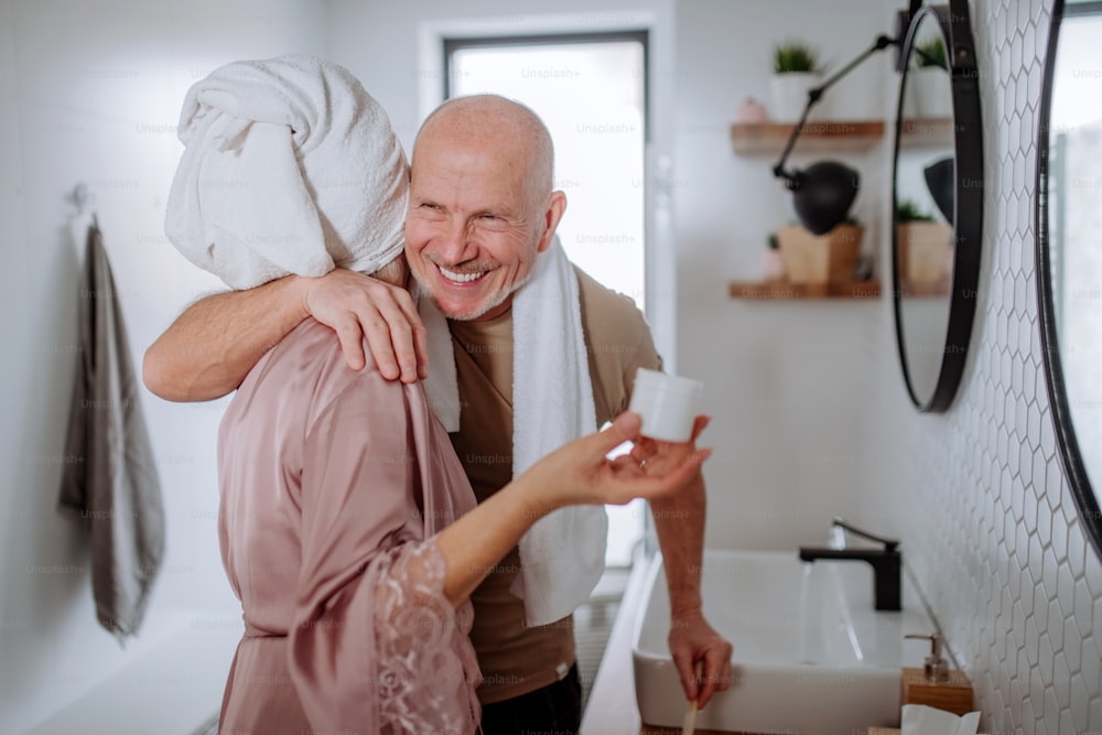 A senior couple in bathroom, brushing teeth and talking, morning routine concept.