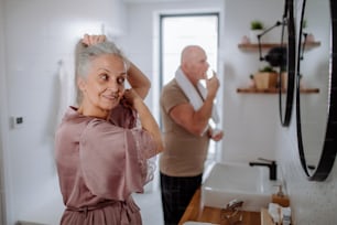 A senior couple in bathroom, brushing teeth and washing, morning routine concept.