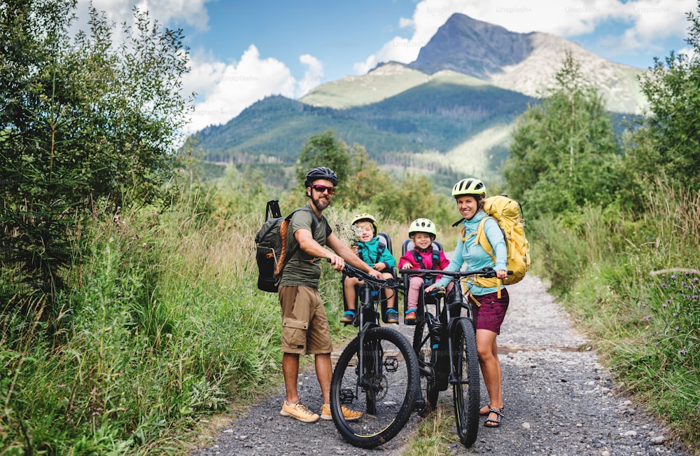 Happy family with small children cycling outdoors in summer nature.