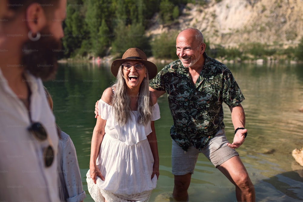 Portrait d’une famille multigénérationnelle heureuse en vacances d’été, s’amusant au bord d’un lac.