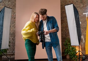Un giovane fotografo mostra le foto alla modella, backstage del servizio fotografico in studio.