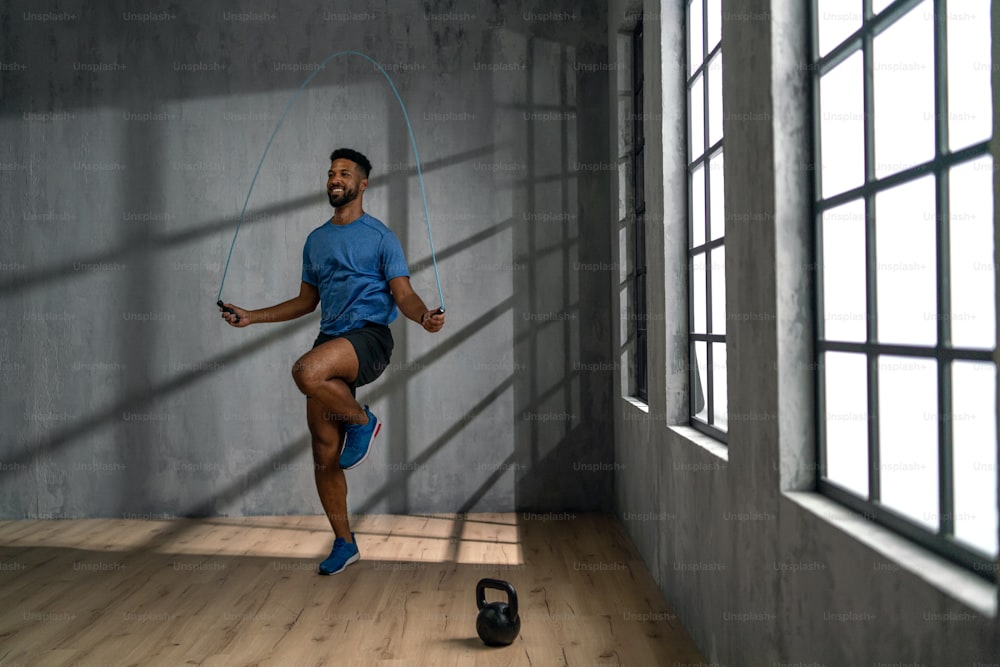 Un jeune sportif afro-américain utilisant une corde à sauter à l’intérieur, concept d’entraînement d’entraînement.
