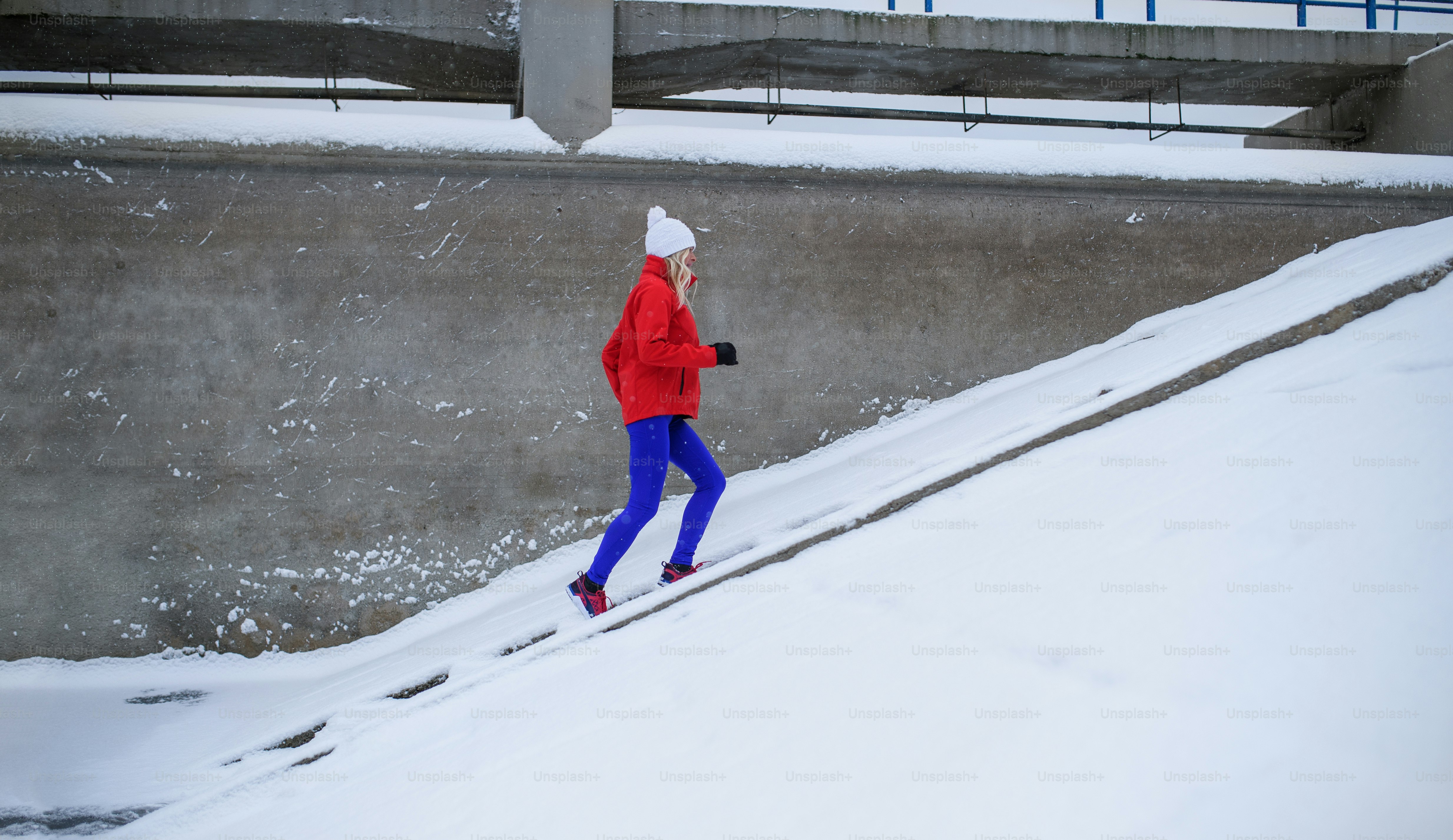 Eine aktive ältere Frau im verschneiten Winter im Freien und macht Sport.