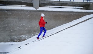 An active senior woman outdoors in snowy winter, doing exercise.