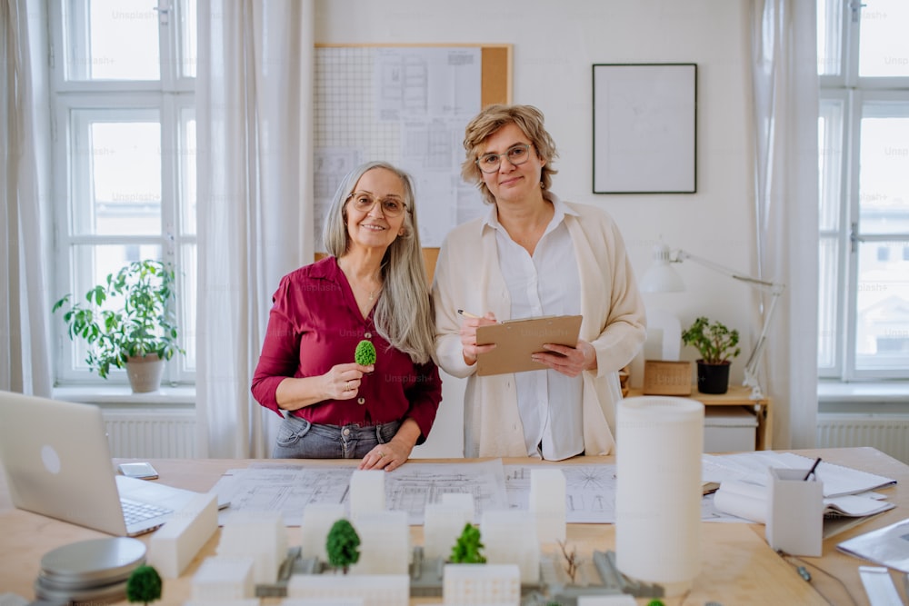 Des femmes architectes d’âge mûr travaillant ensemble dans un bureau, regardant la caméra.