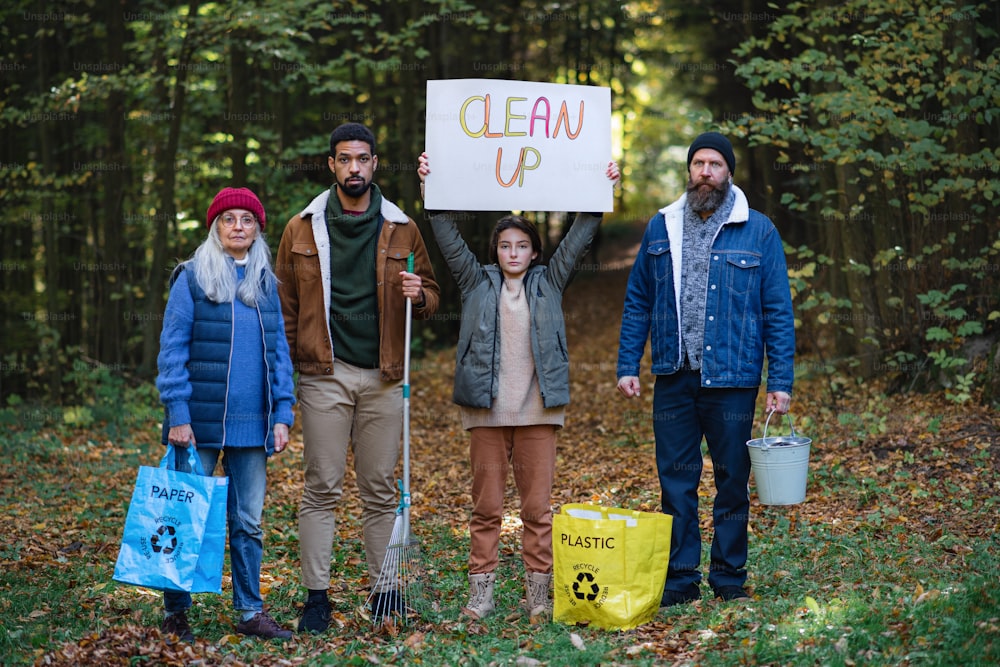 A diverse group of irritated activists ready to clean up forest, holding banner and looking at camera.