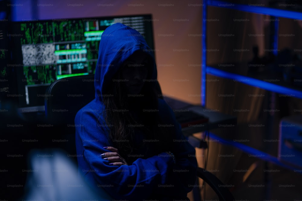 밤에 어두운 방에서 컴퓨터로 두건을 쓴 익명의 해커, 사이버 전쟁 개념.