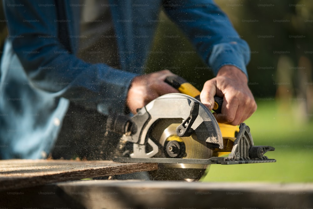 A close-up of craftsman working with circular saw at construction site