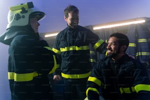 Des pompiers heureux, hommes et femmes, discutant après une action à l’intérieur dans une caserne de pompiers