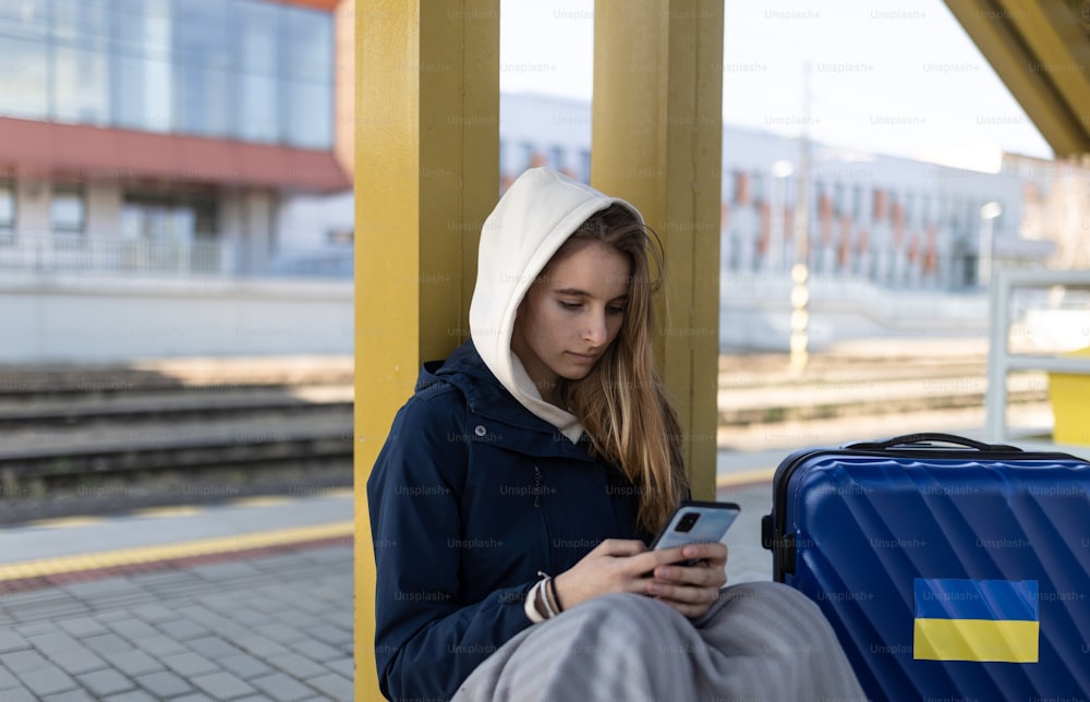 Eine depressive junge ukrainische Immigrantin sitzt und wartet am Bahnhof.